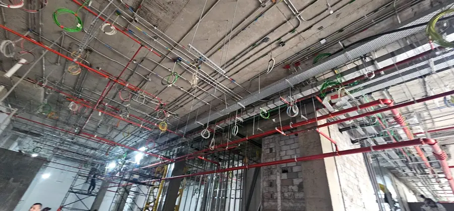Overhead services in a new building, with red sprinkler pipework above the ceiling line