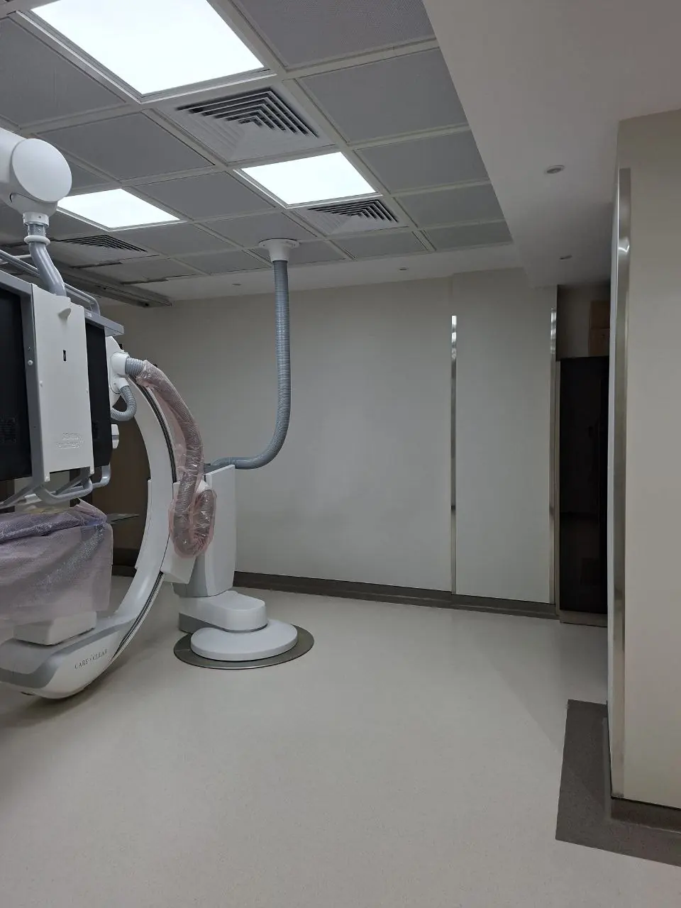 غرفة أشعة تداخلية فيها جهاز بذراع على شكل C وشاشات معلقة بالسقف