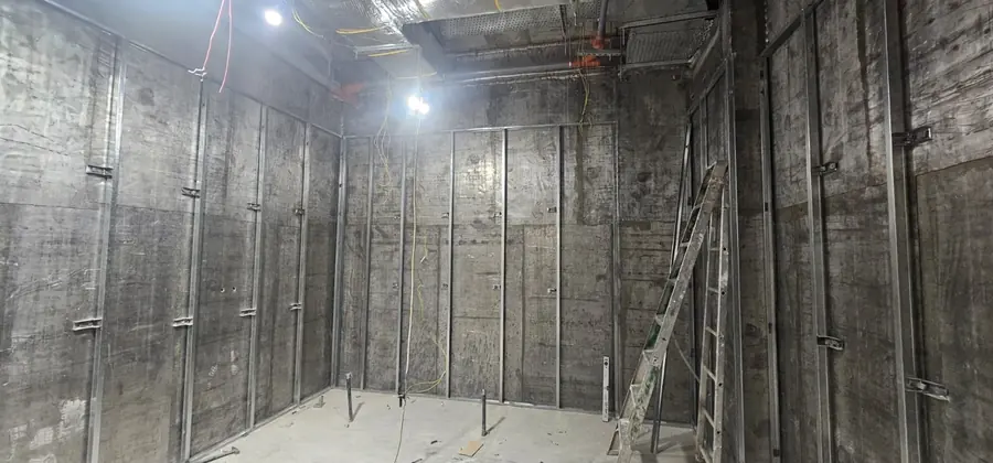 Lead-lined room under construction, with metal studs and a ladder